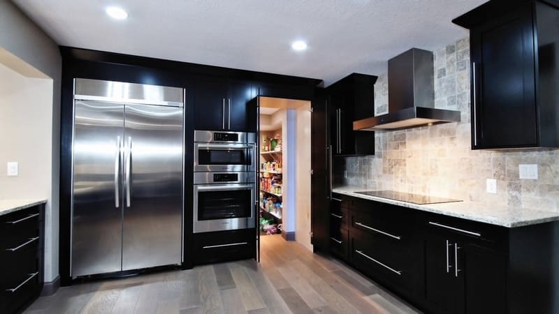A kitchen with black cabinets and stainless steel appliances.