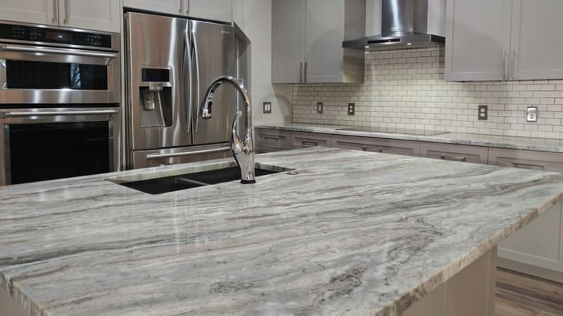 A kitchen with marble counter tops and stainless steel appliances.